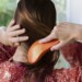 woman brushing her hair while looking at her reflection