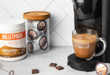 Mug of Bulletproof Sea Salt Hazelnut Mocha sitting on Keurig Machine next to jar of Bulletproof coffee pods and Hazelnut Creamer