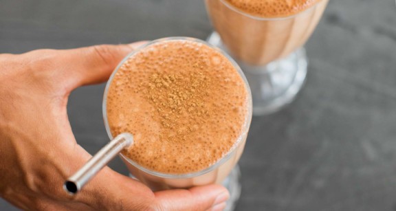 Chocolate collagen milkshake in glass with metal straw