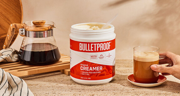 hand reaching for coffee with bulletproof original creamer next to it and a transparent coffee pot