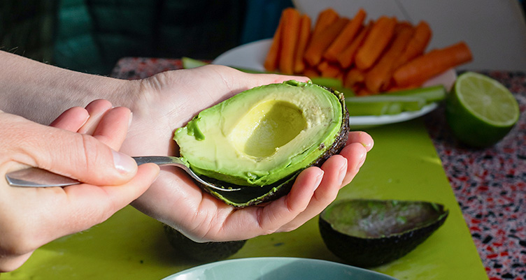 hand scooping out an avocado