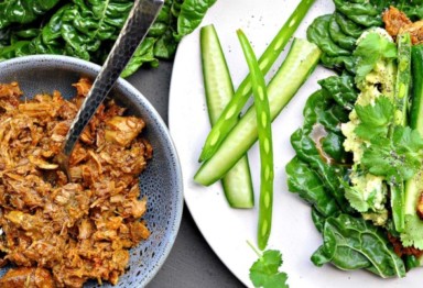 Mexican shredded beef next to white plate of vegetables