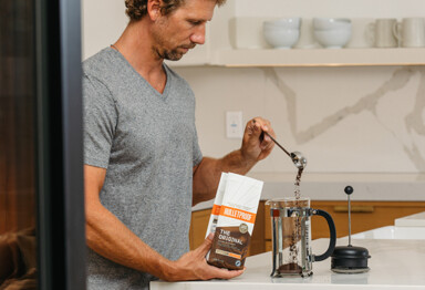 Man scooping Bulletproof coffee into press